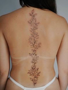 the back of a woman's body with flowers on her left side and behind her