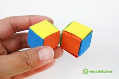 a hand is holding two small cubes in each other's fingers, with one being held by the other