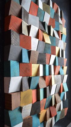 a wooden wall sculpture made out of different colored wood blocks on a black table top