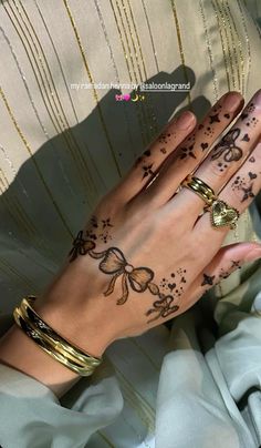 a woman's hand with tattoos on it and gold rings around her wrist,