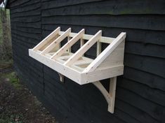 a wooden shelf on the side of a black building with wood framing attached to it