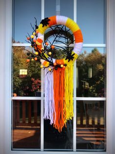 an orange, yellow and white wreath on a window sill