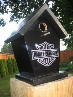 a black birdhouse sitting on top of a wooden post