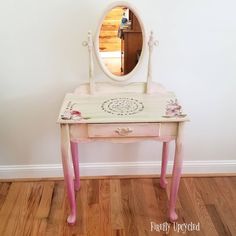 a pink vanity table with a mirror on top and flowers painted on the side, in front of a white wall