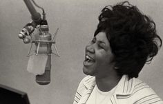 a woman laughing while singing into a microphone