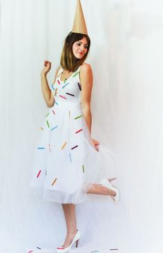 a woman in a white dress with a cone on her head is posing for the camera