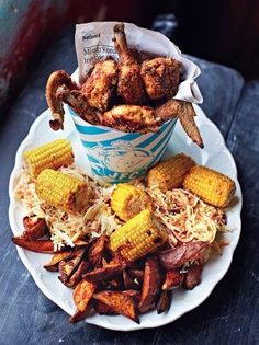 a white plate topped with corn on the cob and fried chicken