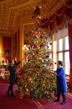 two women are decorating a christmas tree in the state dining room at buckingham palace