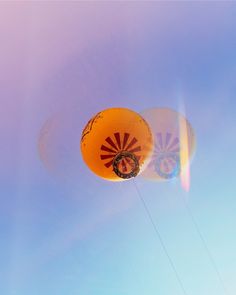 two balloons are flying in the sky on a sunny day