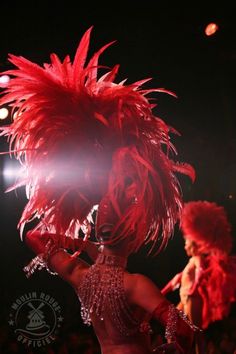 two women in red feathered costumes on stage