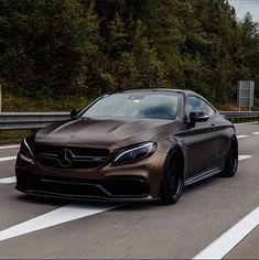 a brown mercedes benz coupe driving down the road