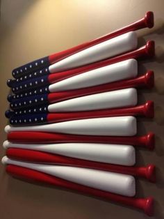 red, white and blue baseball bats lined up against a wall in the shape of an american flag