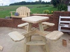 a wooden table and chairs sitting in front of a brick wall with grass behind it