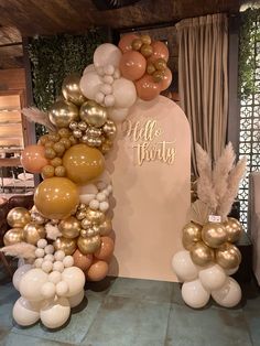 balloon arch with gold and white balloons in front of the entrance to a party venue