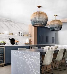 a kitchen with marble counter tops and pendant lights over the island in front of it