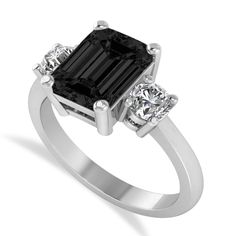 an engagement ring with a black diamond and three diamonds on the side, set in white gold