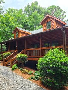 a large log cabin in the woods with stairs leading up to it's second story