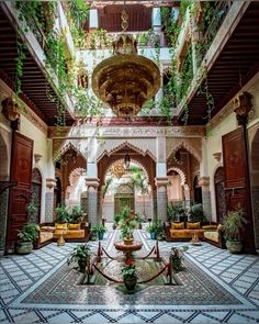 an indoor courtyard with potted plants on the ceiling and tile flooring in front of it