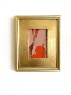 a gold frame with an orange and pink painting in the center on a white wall