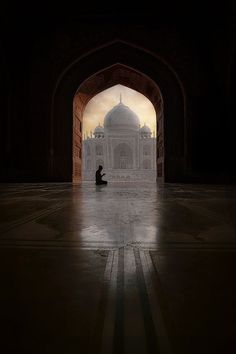 a person sitting on the ground in front of an archway