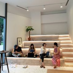 three people sitting on the steps in front of a window