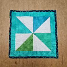 a green and white quilted square on top of a wooden table