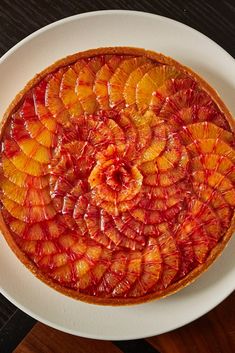 a fruit tart on a white plate sitting on a wooden table