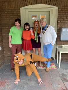 five people posing for a photo in front of a door with the character scooby on it