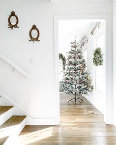 a decorated christmas tree sitting on top of a hard wood floor next to a stair case