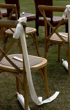 several chairs with bows tied to them in the grass