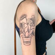 a woman with a tattoo on her arm has a potted plant in front of her shoulder