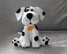 a crocheted stuffed dog sitting on top of a white sheet with black spots