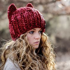 a young woman wearing a red knitted hat with ears on it's head