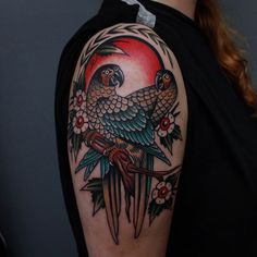 a woman with a tattoo on her arm has a parrot perched on top of a branch