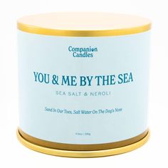 you & me by the sea candle in a tin on a white background with gold trim