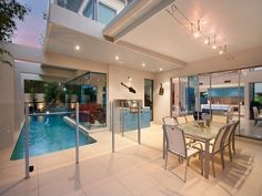 an indoor swimming pool in the middle of a living room and dining area with glass railings