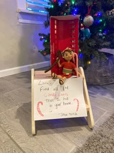 a stuffed animal sitting on top of a chair next to a sign that says, santa's little helper