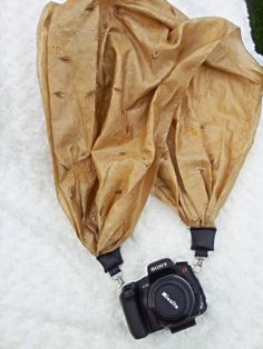 a camera is laying on the snow next to a brown cloth covering it's body