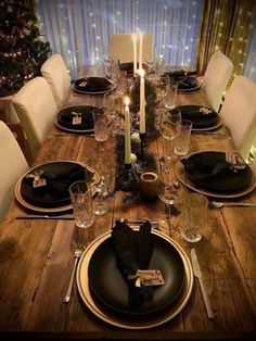 a dining room table is set with black plates and place settings for four people to sit at