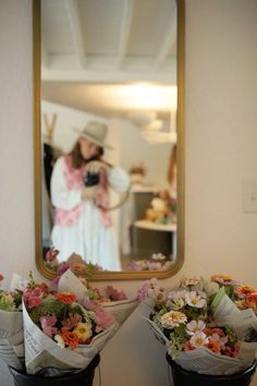 there are flowers in the black buckets on the table and a woman is taking a selfie