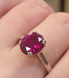 a close up of a person's hand with a pink ring on their finger