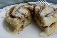 a cinnamon roll on a white plate with a fork