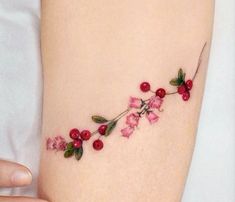 a woman's thigh with pink flowers and leaves on the bottom part of her leg