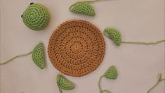 a crocheted green object sitting on top of a white table next to leaves