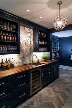 a kitchen with dark cabinets and wooden counter tops, an island in the middle has wine bottles on it