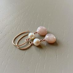 Classic pearls join sparkly pink moonstone. As you can see from my shop, I love mixing up gorgeous gems.  I am really stuck on pink moonstone right now. The smooth round pearls and microfaceted "hearts" sway on rose goldfilled wire and dangle from rose goldfilled earwires.  These earrings are a gorgeous springy mix.  Moonstone gems measure 9mm, pearls measure 6mm, total earring length is 1 + 7/16 inches. Pearl  is a birthstone for June. **Lately moonstones have been available in a variety of uni Luxe Boho, Wire Wrap Jewelry Designs, Pink Moonstone, Earrings Rose Gold, Pearl Pink, Boho Luxe, Moonstone Earrings, Matching Necklaces, Rose Gold Earrings