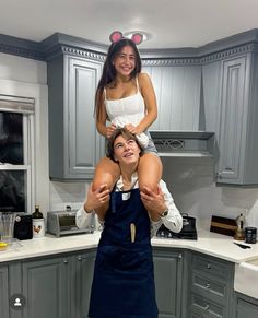 a woman is holding up a man in the kitchen