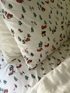 a bed with white sheets and red and green christmas decorations on it, next to a pillow case