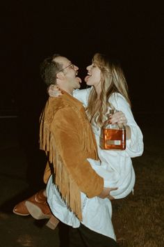 a man holding a woman in his arms while she is wearing a fringed jacket