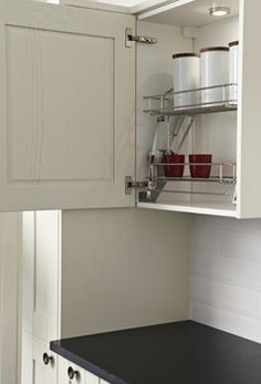 an open cabinet door in a kitchen with black counter top and white cabinets below it